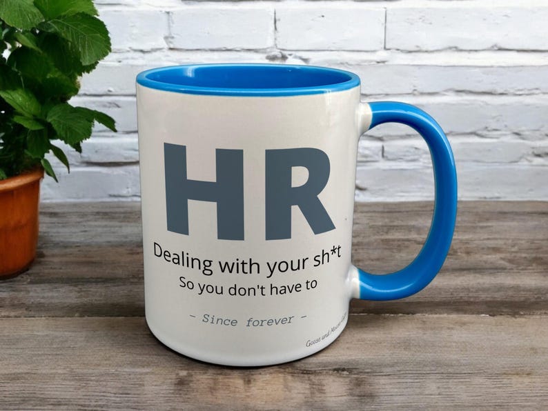 Blue & White Ceramic Mug with HR Design sat on a table. The Cup has a standard handle.