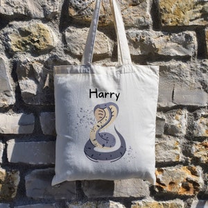 May include: A white canvas tote bag with a grey snake illustration and the name "Harry" printed on the front.