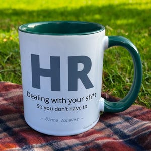 Green & White Ceramic Mug with HR Design sat on a table. The Cup has a standard handle.