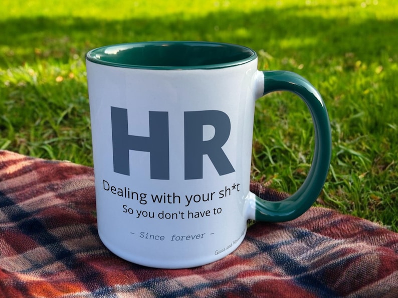 Green & White Ceramic Mug with HR Design sat on a table. The Cup has a standard handle.