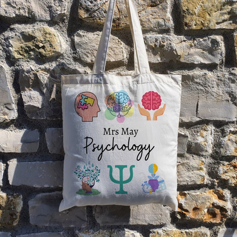 Puede incluir: Una bolsa de lona blanca con un tema de psicolog&iacute;a colorido. La bolsa presenta un cerebro, una pieza de rompecabezas, un s&iacute;mbolo de psicolog&iacute;a y el texto "Mrs. May Psychology".