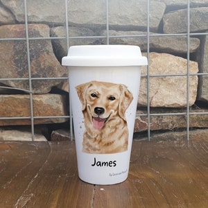 K&ouml;nnte beinhalten: Wei&szlig;e Keramik-Reisebecher mit einer Aquarell-Illustration eines Golden Retriever-Hundes. Der Becher hat einen schwarzen Deckel und der Name "James" ist unten aufgedruckt.