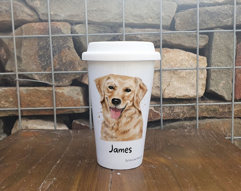 K&ouml;nnte beinhalten: Wei&szlig;e Keramik-Reisebecher mit einer Aquarell-Illustration eines Golden Retriever-Hundes. Der Becher hat einen schwarzen Deckel und der Name "James" ist unten aufgedruckt.