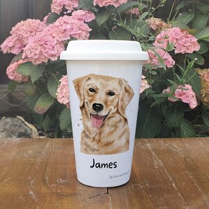 K&ouml;nnte beinhalten: Wei&szlig;e Reisebecher mit einer Aquarell-Illustration eines Golden Retriever Hundes. Der Becher tr&auml;gt den Namen "James" auf der Unterseite.