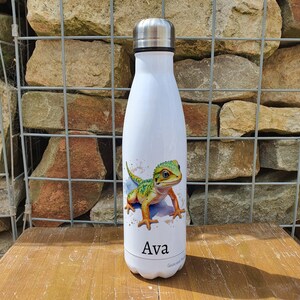 May include: White stainless steel water bottle featuring a green and yellow lizard illustration and the name "Ava" printed on the bottom.