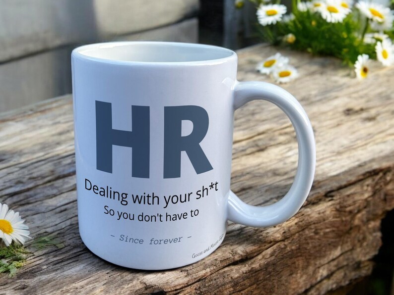 White Ceramic Mug with HR Design sat on a table. The Cup has a standard handle.