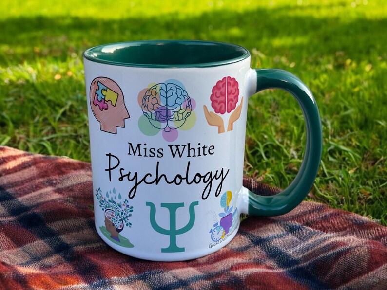 Green & White Ceramic Mug with Psychology Design sat on a table. The Cup has a standard handle. Customisable text is printed below the Psychology design in a black text.