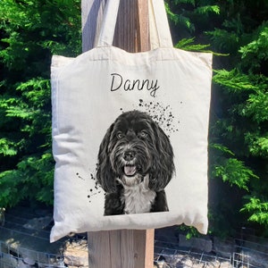 May include: A white canvas tote bag with black handles. The bag features a black and white illustration of a dog with the name "Danny" printed on the front.