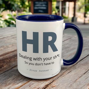 Navy & White Ceramic Mug with HR Design sat on a table. The Cup has a standard handle.