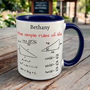May include: White ceramic mug with a navy blue interior and handle. The mug features the name "Bethany" and the phrase "The simple rules of life" in red. Mathematical formulas and diagrams are printed on the mug.