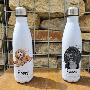 May include: Two white stainless steel water bottles with personalised dog portraits. The bottle on the left has a brown and white dog with the name "Poppy" printed on it. The bottle on the right has a black and white dog with the name "Danny" printed on it.