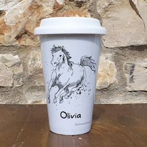 May include: White ceramic travel mug with a black and white illustration of a horse running. The mug has a black lid and the name "Olivia" is printed on the bottom in black lettering. The text "By Goose and Mouse" is printed below the name.