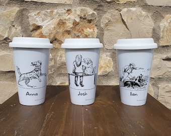 May include: Three white ceramic travel mugs with black and white illustrations and names. The mugs are on a wooden surface. The mugs are labeled "Anna", "Josh", and "Ian".