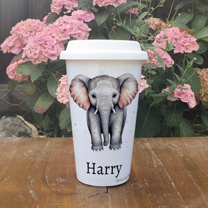 May include: White travel mug featuring a watercolour illustration of an elephant with the name "Harry" printed on the base.