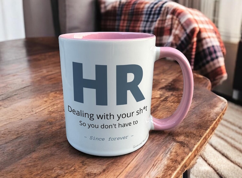 Pink & White Ceramic Mug with HR Design sat on a table. The Cup has a standard handle.