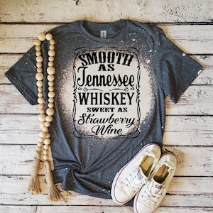 May include: A gray t-shirt with a bleach-splattered design featuring the text "Smooth as Tennessee Whiskey Sweet as Strawberry Wine".