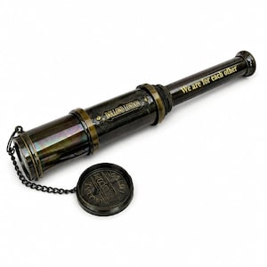 Peut inclure: Un télescope à main en métal foncé avec des accents en laiton, doté d'un capuchon amovible attaché par une chaîne. Le corps porte l'inscription DOLLOND LONDON et la phrase We are for each other, tandis que le capuchon affiche ROYAL TELESCOPE LONDON.