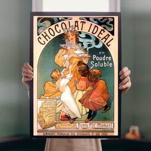 Op de afbeelding: Vintage reclame voor Chocolat Ideal, een merk van chocoladepoeder. De advertentie toont een vrouw in een gele jurk die chocolade serveert aan drie kinderen. De tekst luidt "Chocolat Ideal en Poudre Soluble" en "Donne P'tit Maman!" De advertentie is in een kleurrijke Art Nouveau-stijl.