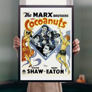 Puede incluir: Un póster de película vintage enmarcado para "The Cocoanuts" con los Hermanos Marx. El póster tiene una imagen central en forma de diamante de los actores, con dos mujeres bailando a cada lado. El póster está en un marco negro.