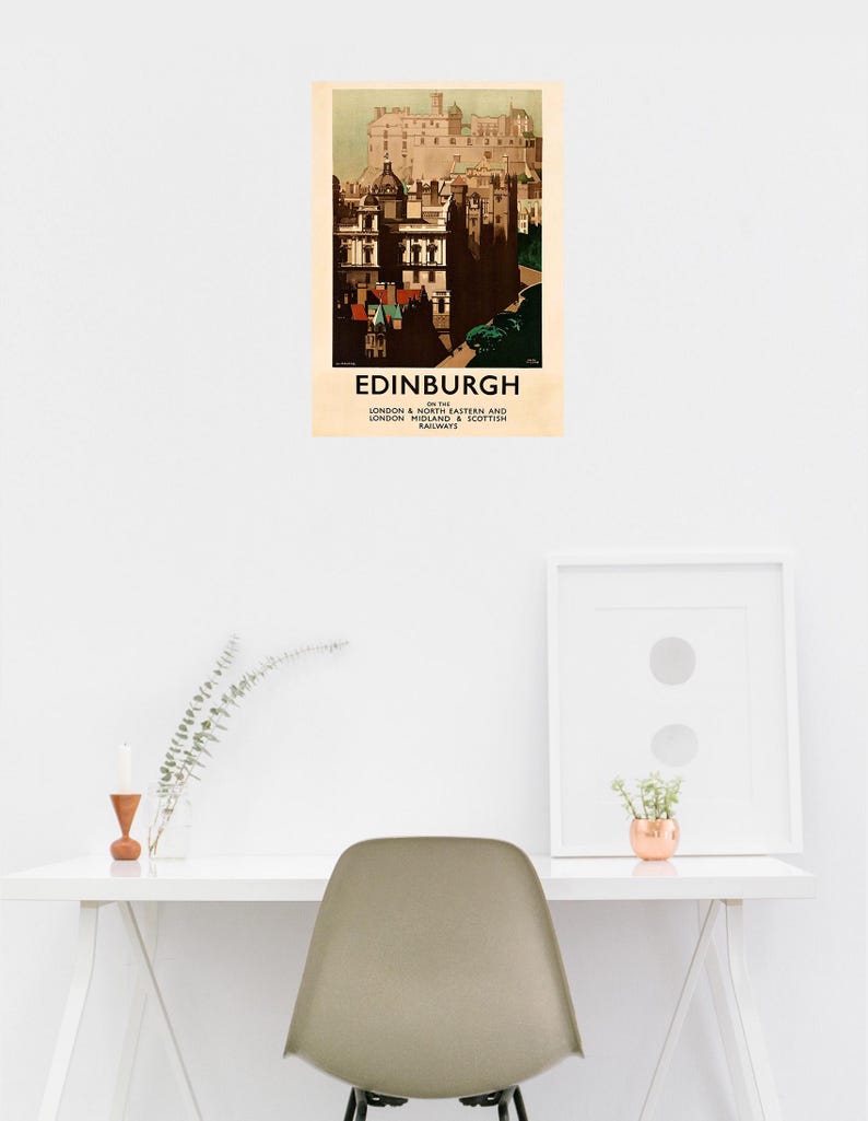 Op de afbeelding: Een vintage reisposter voor Edinburgh, Schotland, met een gedetailleerde illustratie van de architectuur van de stad. De poster heeft een cr&egrave;mekleurige achtergrond met het woord "EDINBURGH" onderaan. De poster wordt op een witte muur weergegeven.