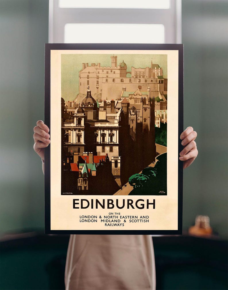Op de afbeelding: Een ingelijste vintage reisprent voor Edinburgh, Schotland, met een gedetailleerde illustratie van de architectuur van de stad. De poster heeft een beige achtergrond en het woord "Edinburgh" in vette letters. De poster is zwart omlijst.