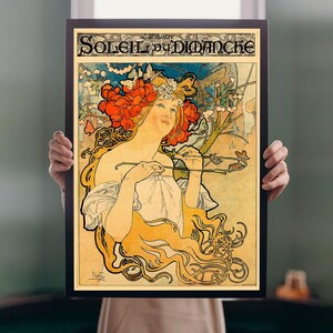 May include: Framed art print featuring a vintage illustration titled "Soleil du Dimanche." The artwork showcases a woman with flowing golden hair and a floral headdress, holding a branch. The color palette includes reds, yellows, and blues.