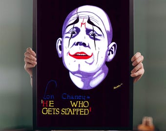 May include: A framed poster featuring a stylized portrait of Lon Chaney as a clown from the film "He Who Gets Slapped." The artwork has a dark background with the title in yellow and blue text. The clown has white face paint, red lips, and black accents.
