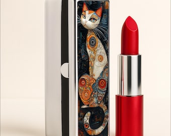 May include: A rectangular lipstick case with a silver and black frame featuring a detailed, colorful illustration of a cat with orange, white, and blue geometric patterns. Beside it stands a tube of vibrant red lipstick in a metallic silver and red casing.