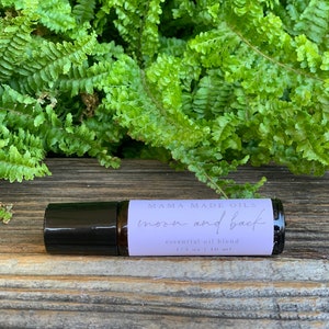 May include: A purple roll-on bottle with a black cap labeled "Mama Made Oils moon and back essential oil blend 1/3 oz | 10 ml"