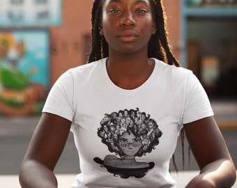 Puede incluir: Una camiseta blanca de manga corta con un estampado gráfico en blanco y negro en el pecho. El diseño muestra la silueta estilizada de una persona con un gran peinado afro compuesto por varios retratos pequeños, con el texto MY ROOTS visible.