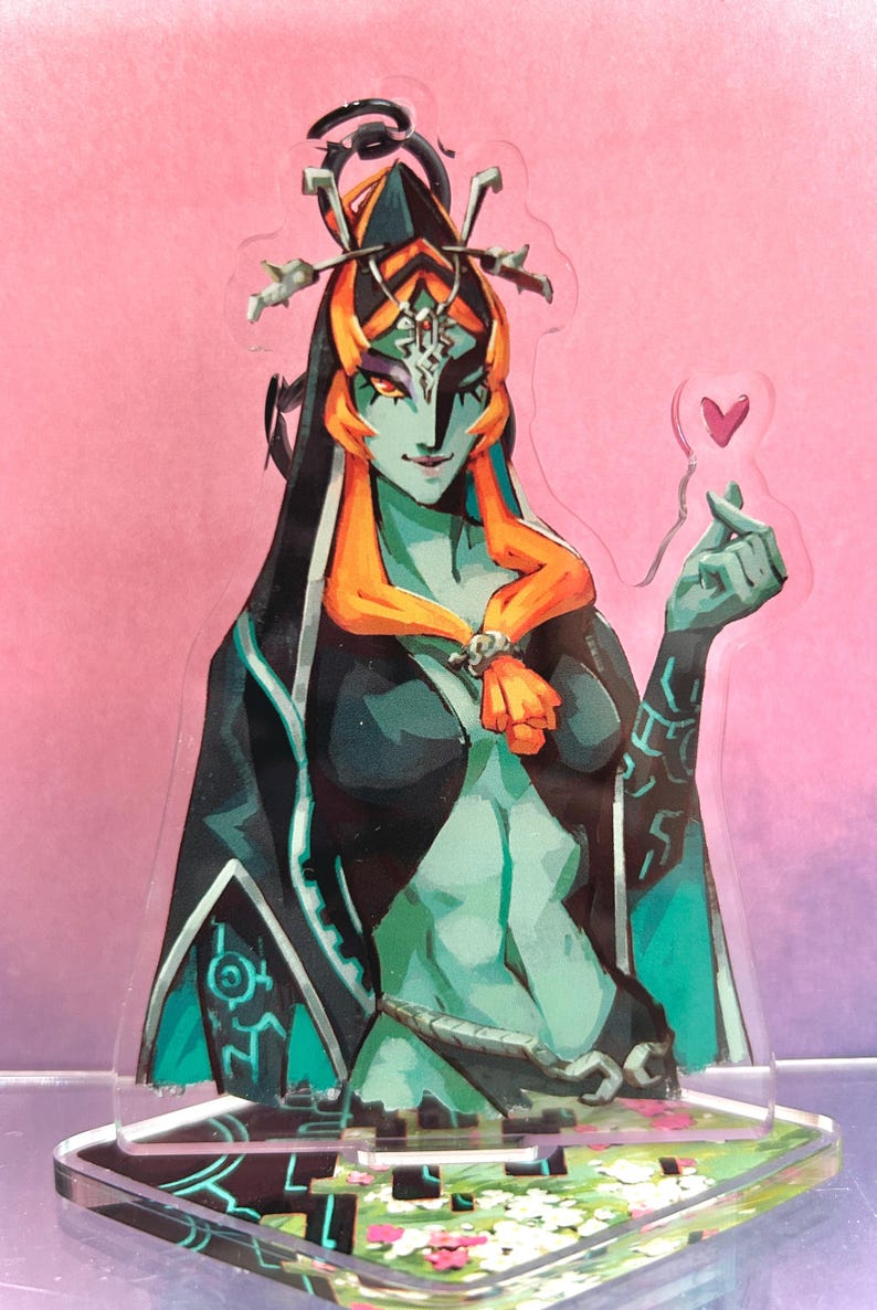 May include: Acrylic standee featuring a teal-skinned character with orange hair and a black outfit. The character holds a heart-shaped object. The standee has a decorative base with floral accents and geometric designs.