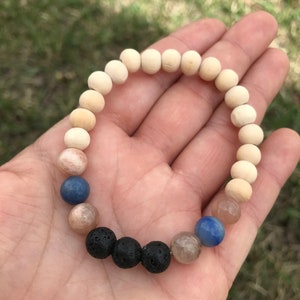 May include: A bracelet made of natural wood beads, sunstone beads, blue agate beads, and black lava rock beads.