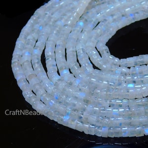May include: A strand of white moonstone beads with an iridescent sheen. The beads are square shaped and have a smooth, polished finish.