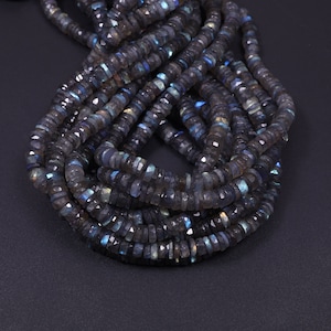 May include: A strand of dark gray faceted labradorite beads. The beads have a iridescent sheen with hints of blue and green.