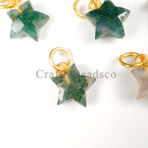 May include: Close-up of several star-shaped pendants. Each pendant features a faceted, green stone with gold-colored metal loops for hanging. The text "CraftNBeadsco" is visible in the image.