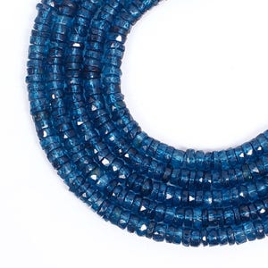 Puede incluir: Primer plano de hebras de cuentas de piedras preciosas facetadas de color azul oscuro. Las cuentas son pequeñas, en forma de disco, y están ensartadas, creando un efecto texturizado y en capas. El color es un azul rico y saturado, con sutiles variaciones de tono. Ideal para la fabricación de joyas.