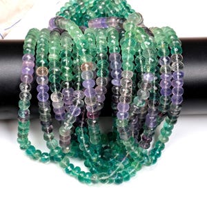 May include: A strand of faceted fluorite beads in shades of green, purple, and clear. The beads are approximately 4mm in diameter and have a smooth, polished finish.