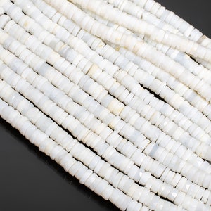 May include: Close-up of strands of white, disc-shaped beads. The beads have a slightly faceted surface and are strung together, creating a textured, layered effect. The beads are a neutral white color, suitable for jewelry making.