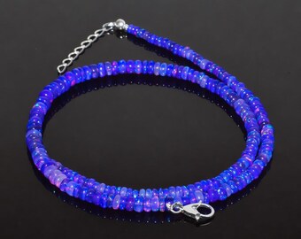 May include: A vibrant blue opal bead necklace with a silver clasp. The necklace is composed of small, round beads that create a layered effect. The beads have a shimmering, iridescent quality, with hints of purple and pink.
