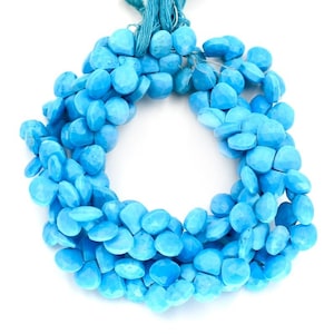 May include: A strand of turquoise gemstone beads, each bead is a faceted, teardrop shape. The beads are a vibrant blue color and are strung on a thin, blue thread.
