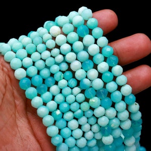 May include: A strand of light blue faceted gemstone beads. The beads are round and have a smooth, polished finish.