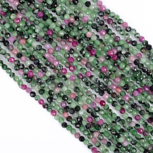 Puede incluir: Una hebra de cuentas de piedras preciosas facetadas de color verde y rosa. Las cuentas son pequeñas y redondas, y están enhebradas en un hilo transparente.