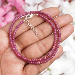 May include: A delicate double strand necklace made with small pink ruby beads and a silver clasp.