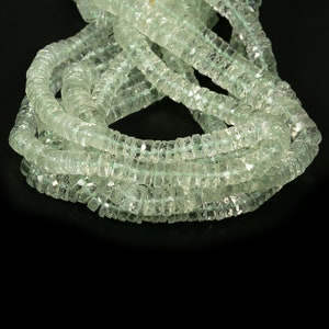 May include: A strand of light green gemstone beads, each bead is faceted and has a square shape.