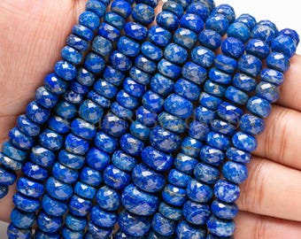 May include: A collection of faceted, round, disc-shaped lapis lazuli beads in a deep royal blue color with natural gold-colored pyrite inclusions, arranged in multiple vertical strands to showcase their polished, reflective surfaces.