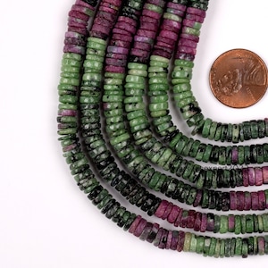 May include: A strand of green and pink gemstone beads. The beads are round and have a speckled pattern. The beads are strung on a wire and are approximately 6mm in diameter.
