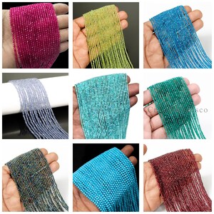 Puede incluir: Nueve hebras de pequeñas cuentas facetadas en varios colores, incluyendo rosa, amarillo-verdoso, turquesa, azul claro, verde azulado, verde oscuro, iridiscente, azul brillante y burdeos. Las cuentas se sostienen en una mano, mostrando su color y textura.