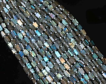 May include: A strand of rectangular labradorite beads featuring a faceted surface with iridescent flashes of blue, gold, and green. The semi-precious stones are arranged in multiple parallel rows and separated by small white spacers on a string.