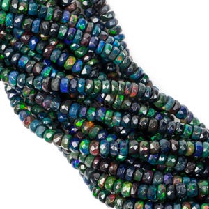May include: A strand of faceted black opal beads with iridescent green, blue, and red hues. The beads are approximately 4mm in size and have a faceted, teardrop shape.