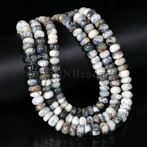 May include: A strand of white and black opal beads. The beads are round and have a speckled pattern. The beads are strung on a clear thread.